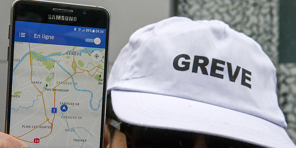 Ein streikender Chauffeur zeigt am Mittwoch vor dem Genfer Sitz von Uber in Carouge die Smartphone-Applikation des Fahrdienstes.
