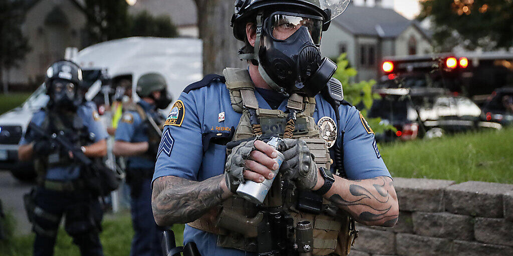 Ein Polizeibeamter mit Gasmaske bereitet sich darauf vor, Tränengas gegen Demonstranten einzusetzen während der Proteste nach dem Tod von George Floyd, der in Folge einer brutalen Festnahme durch einen Polizisten in Minneapolis starb. Ein weißer Polizist hatte bei der Festnahme lange auf dem Hals des Afroamerikaners gekniet, welcher mehrmals darauf aufmerksam machte, dass er nicht atmen könne. Foto: John Minchillo/AP/dpa