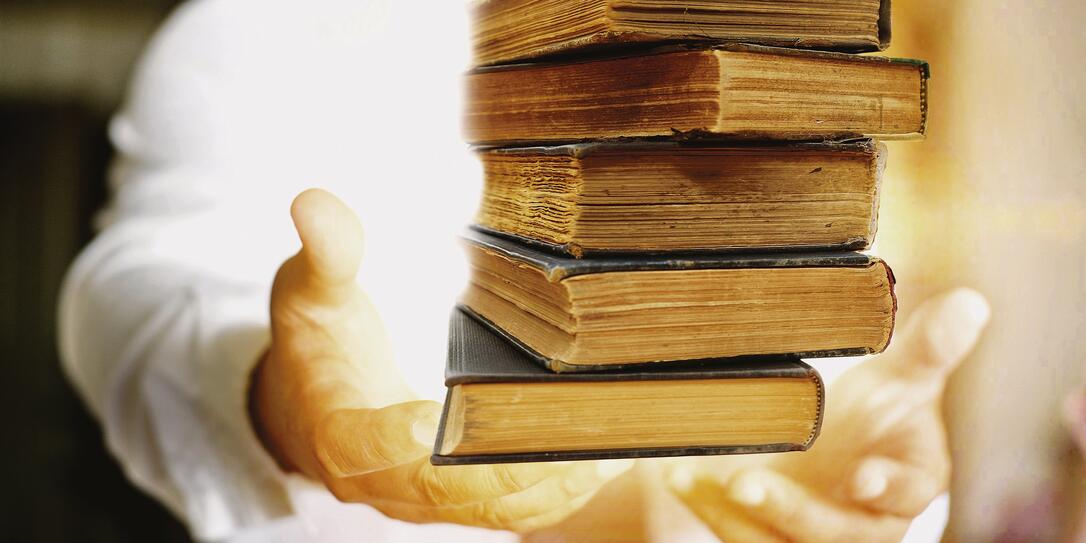 book in man's hands in gesture of giving.