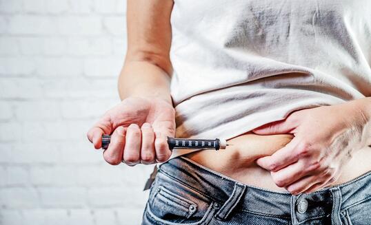 A woman injects insulin with insulin injection device into the subcutaneous tissue of abdomen