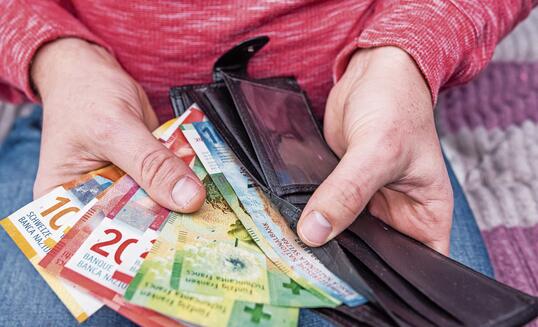 Swiss franc banknotes held in hands with black wallet