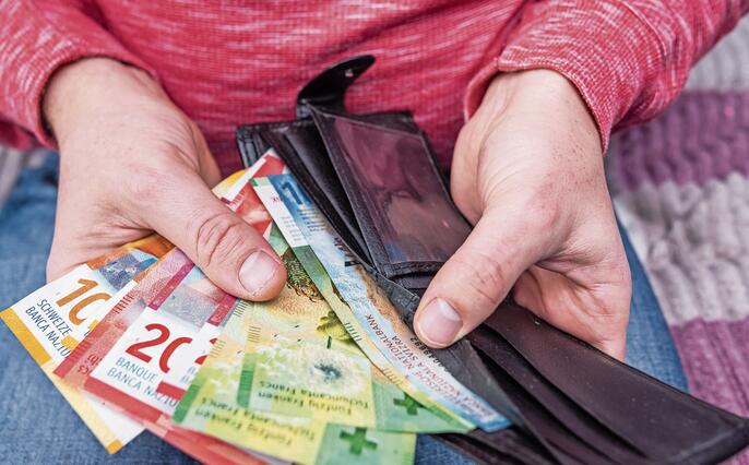 Swiss franc banknotes held in hands with black wallet