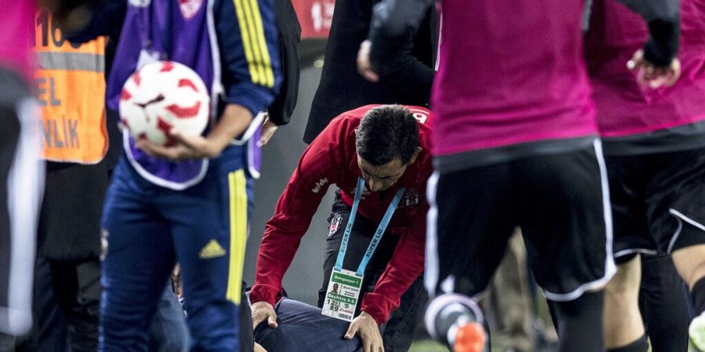 Besiktas-Coach Senol Günes krümmt sich nach dem Messerwurf vor Schmerz auf dem Rasen