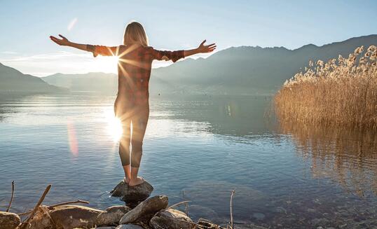 Young woman embracing nature, mountain lake