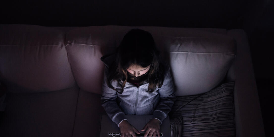 Little girl, sitting in a dark, playing with laptop