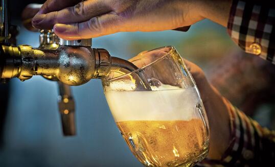 Male bartender pouring beer into glass