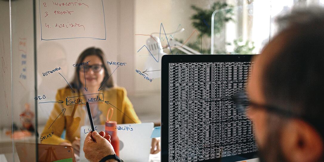Business colleagues discussing plan on glass wall partition