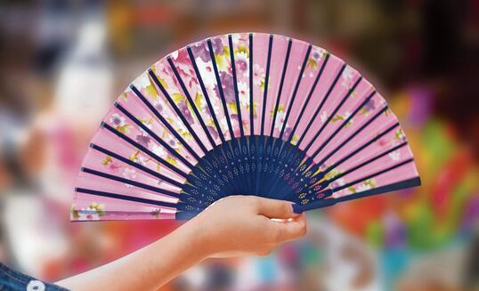 Hand holding fan on small shop blur background.