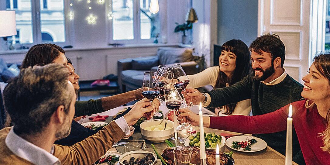 friends clinking wine glasses at festive christmas table