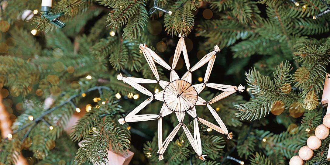 Decorative straw star ornament on a green Christmas tree adorned with lights