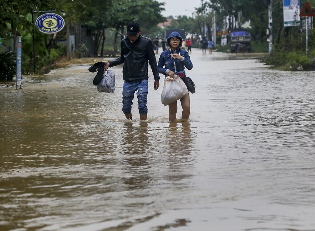 Ein Paar watet durch eine überflutete Strasse in Hoi An.