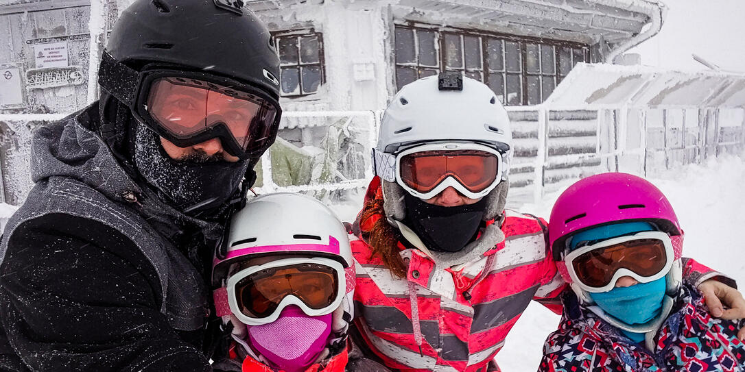 Family on winter vacations taking selfie on mountain slope.