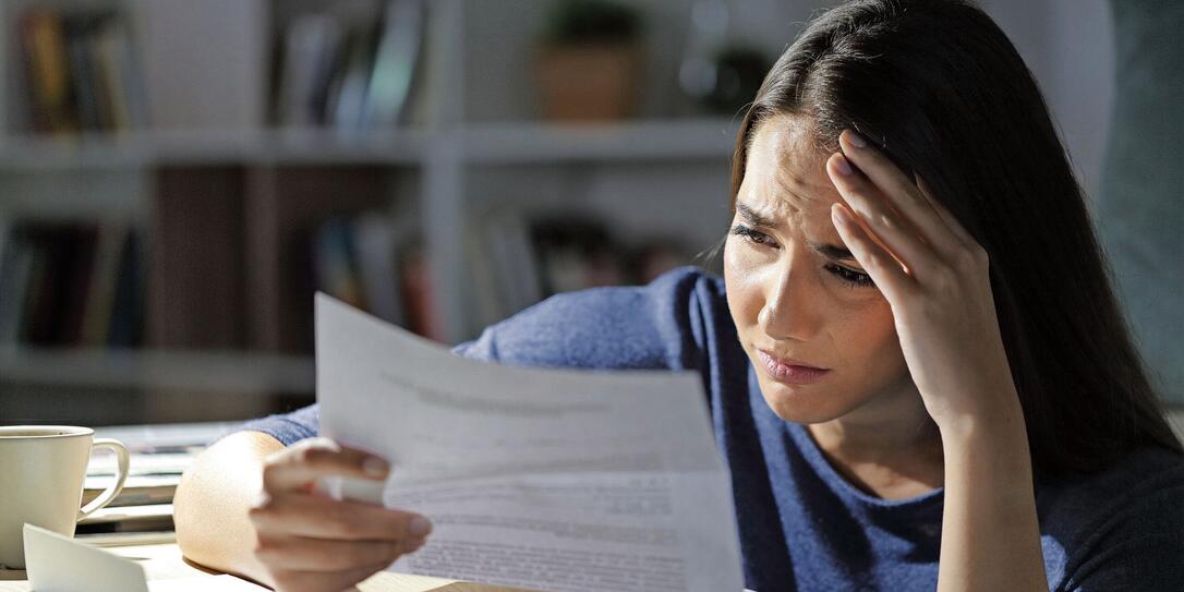 Worried girl reads bad news on letter at night at home
