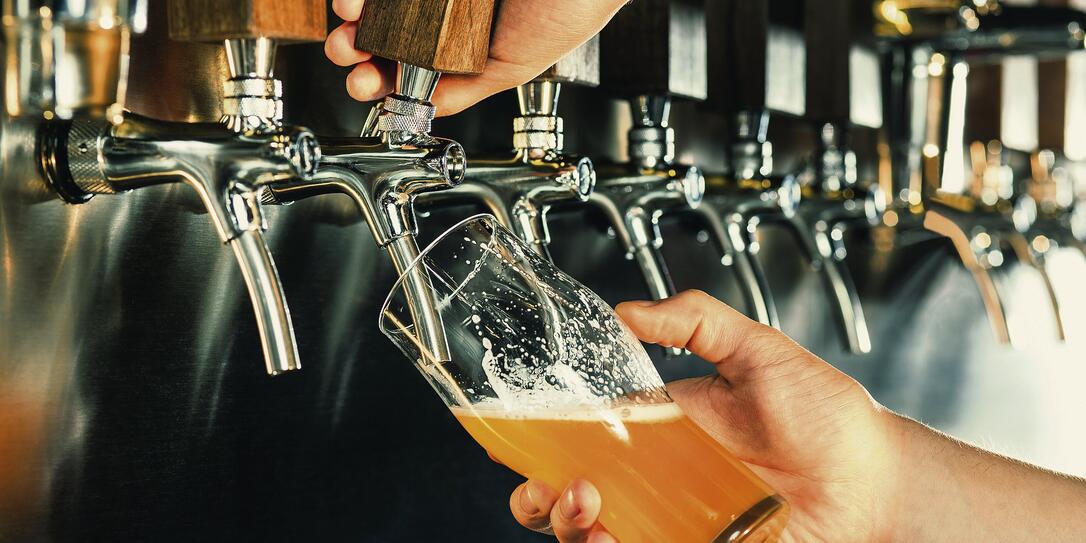 Hand of bartender pouring a large lager beer in tap