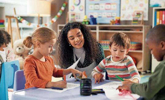 Drawing, education and teacher with children in classroom for learning, students and creative art. Growth, kindergarten and academy with woman and kids at school for helping and child development