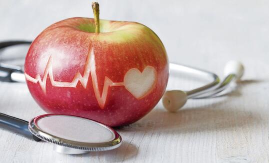 Heartbeat line on red apple and stethoscope, healthy heart diet concept