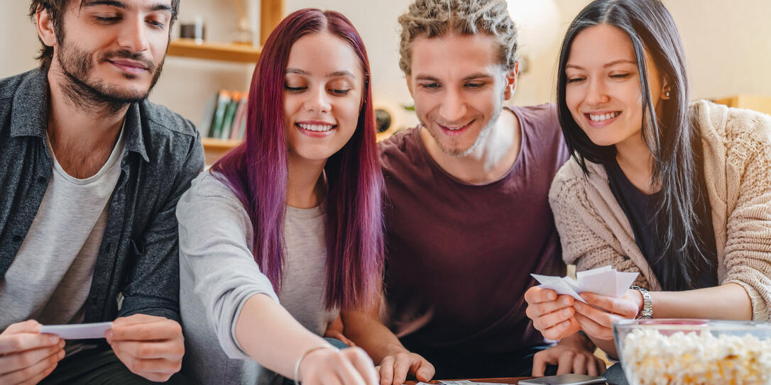 Young group of friends playing board game on table at home interior