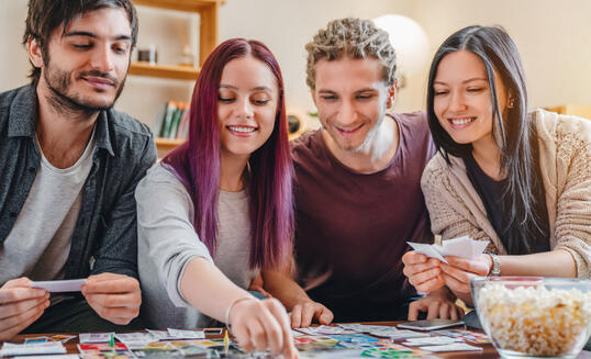 Young group of friends playing board game on table at home interior