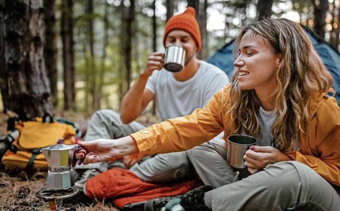 Young couple making coffee during hiking