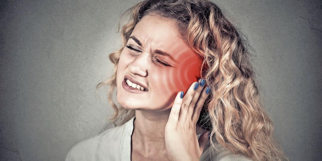 Tinnitus. Sick female having ear pain touching head