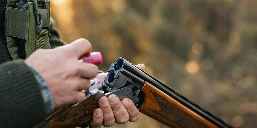 Hunter man loading his gun while hunting outdoors. Hunter man loading his gun while hunting outdoors.
