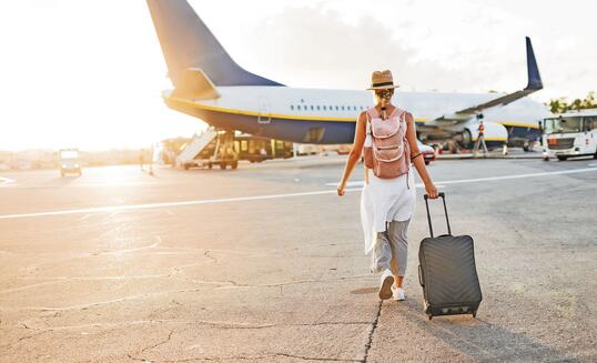Back view of a woman walking towards the plane, ready to board and begin her vacation
