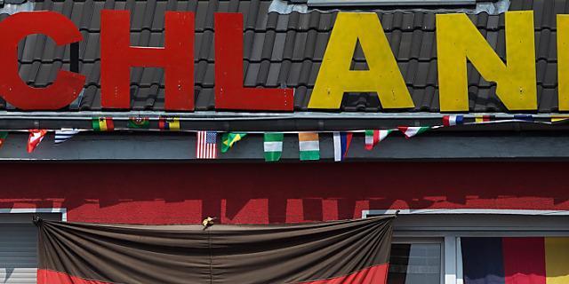 Bewohner dekorieren ihr Haus mit Fahnen und dem Wort "Schland"