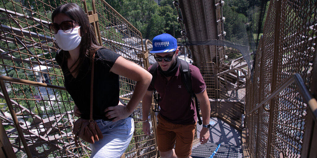 Touristen steigen eine Treppe des Eiffelturms empor. Nach einer über dreimonatigen Zwangspause wegen der Corona-Krise hat der Pariser Eiffelturm am Donnerstag seine Pforten wieder geöffnet. Besucher können zunächst nur über die Treppen den zweiten Stock des Turms erreichen, die Aufzüge sollen erst vom 1. Juli an wieder öffnen. Foto: Andreina Flores/SOPA Images via ZUMA Wire/dpa