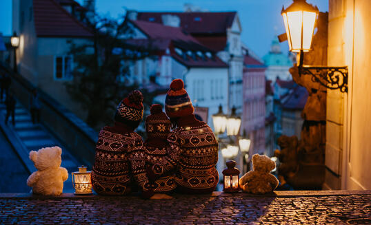 Beautiful children, three boy brothers, casually dressed, looking at night view of Prague city