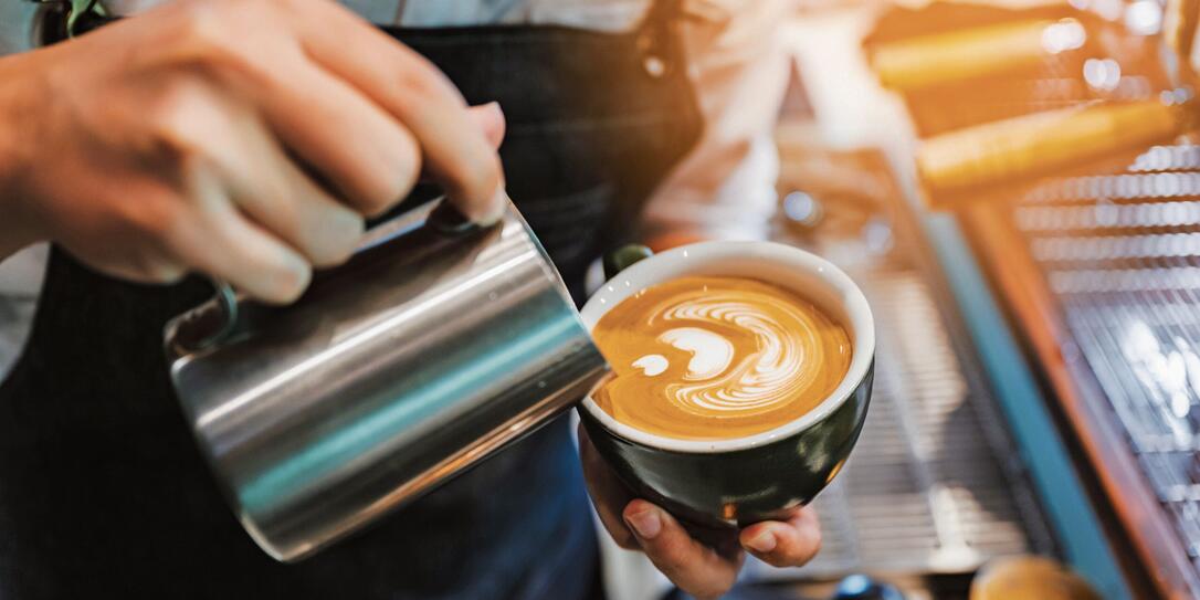 barista making latte art, shot focus in cup of milk and coffee, vintage filter image