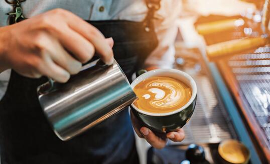 barista making latte art, shot focus in cup of milk and coffee, vintage filter image