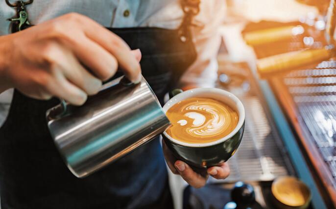 barista making latte art, shot focus in cup of milk and coffee, vintage filter image