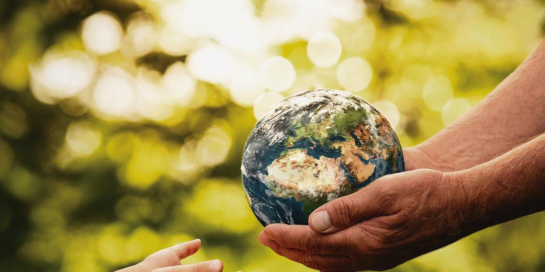 Senior hands giving small planet earth to a child