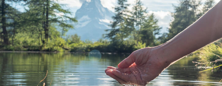Hands scooping water from alpine lake