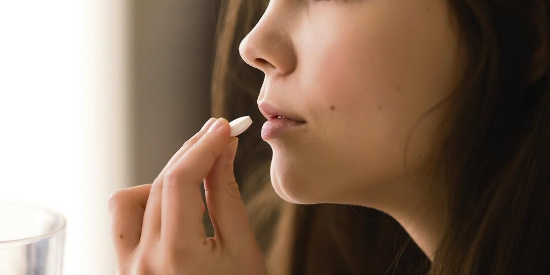Close up image of woman drinking round white pill