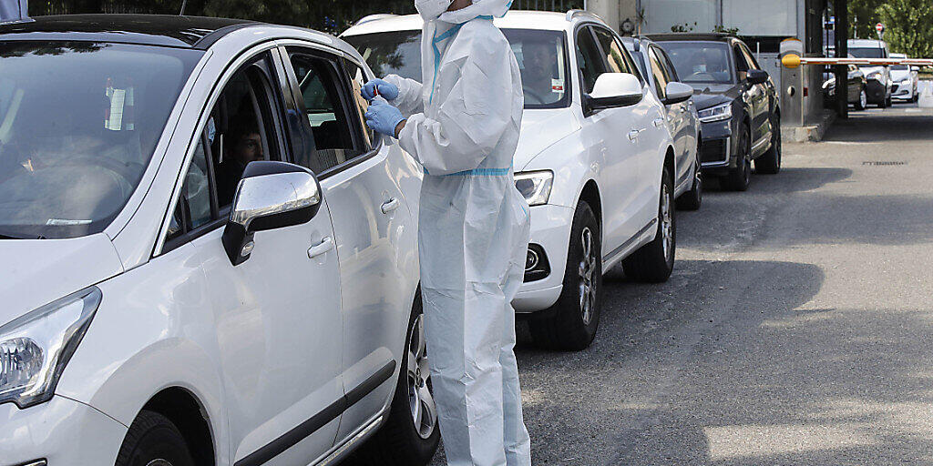 Ein medizinischer Mitarbeiter im Schutzanzug entnimmt an einer Drive-Thru-Station vor dem San Carlo Borromeo Krankenhaus Abstriche für Corona-Tests. Foto: Luca Bruno/AP/dpa Ein medizinischer Mitarbeiter im Schutzanzug entnimmt an einer Drive-Thru-Station vor dem San Carlo Borromeo Krankenhaus Abstriche für Corona-Tests. Foto: Luca Bruno/AP/dpa