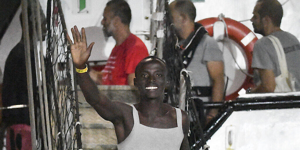 Ein Migrant winkt, als er das spanische Rettungsschiff "Open Arms" im italienischen Hafen von Lampedusa verlässt.