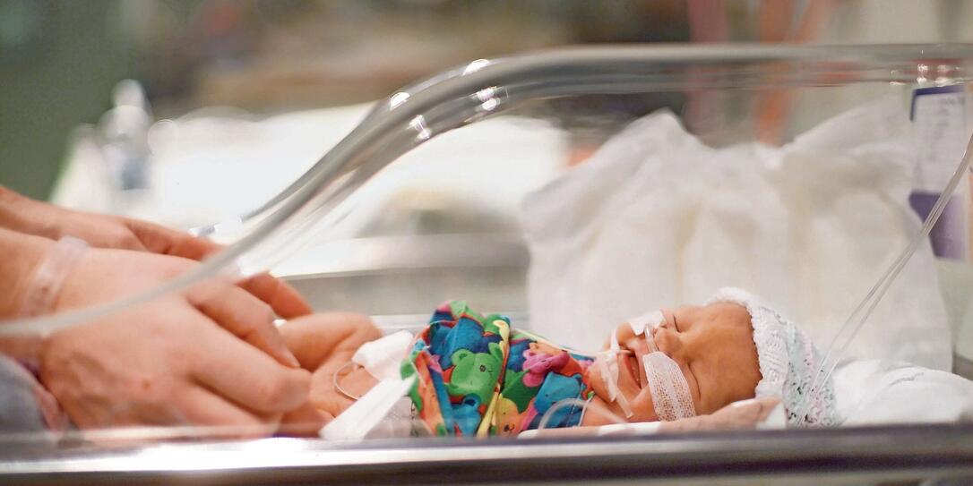 Side view of an incubator with a crying premature baby Side view of an incubator with a crying premature baby