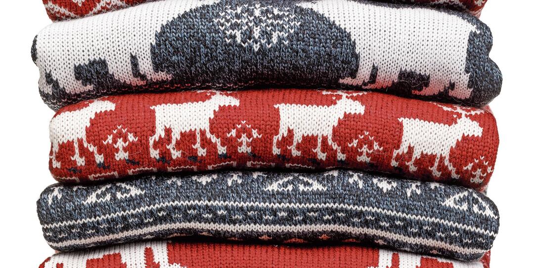 Stack of folded knitted Christmas turtleneck sweaters on white background Stack of folded knitted Christmas turtleneck sweaters on white background