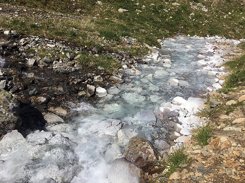 Ein Bergbach im Engadin ist über mehrere Kilometer weiss gefärbt.