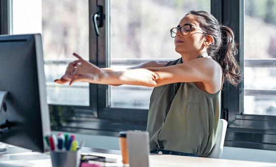 Tired businesswoman stretching body for relaxing while working with computer in the office.
