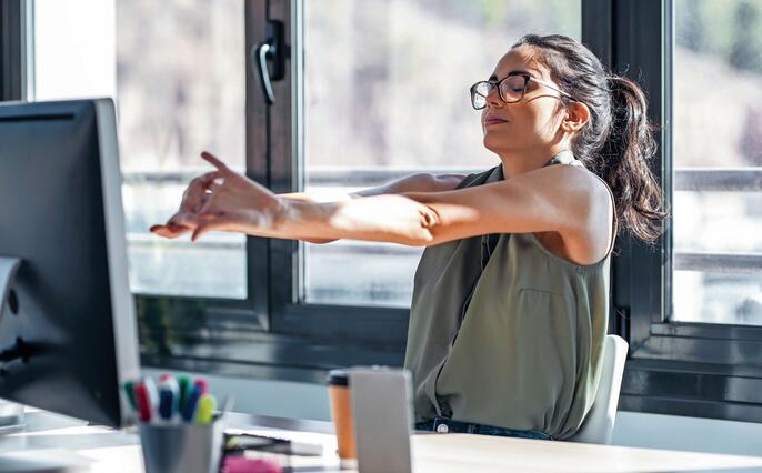 Tired businesswoman stretching body for relaxing while working with computer in the office.