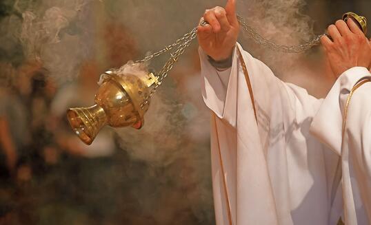 Priest incenses the altar with incense during Holy Mass