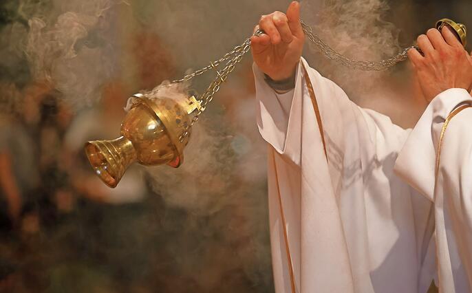 Priest incenses the altar with incense during Holy Mass