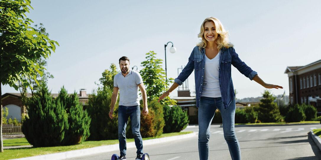 Happy husband and wife riding self-balancing scooters