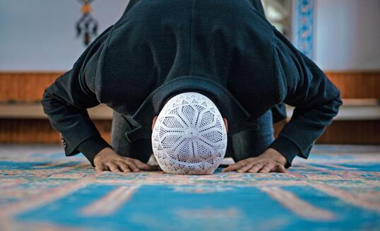 Close-up shot of a Muslim young man worshiping in a mosque