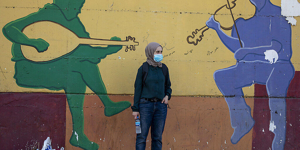 Eine Frau mit Mundschutz wartet vor einer Wand, auf das ein musikalisches Graffiti gemalt ist, auf den Bus. Wenige Tage vor einem Lockdown ist in Israel die Zahl der täglichen Corona-Neuinfektionen erneut auf einen Rekordwert gestiegen. Foto: Ariel Schalit/AP/dpa Eine Frau mit Mundschutz wartet vor einer Wand, auf das ein musikalisches Graffiti gemalt ist, auf den Bus. Wenige Tage vor einem Lockdown ist in Israel die Zahl der täglichen Corona-Neuinfektionen erneut auf einen Rekordwert gestiegen. Foto: Ariel Schalit/AP/dpa