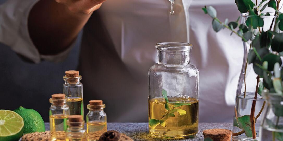 Woman hand pouring eucalyptus essential oil into bottle on grey table Woman hand pouring eucalyptus essential oil into bottle on grey table