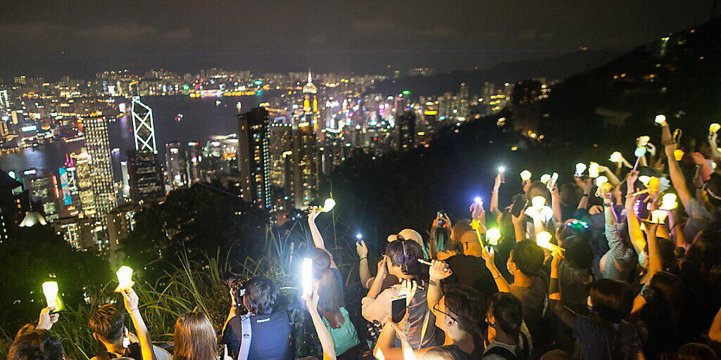 Regierungskritiker in Hongkong bilden am Victoria Peak eine Menschen- und Lichterkette.