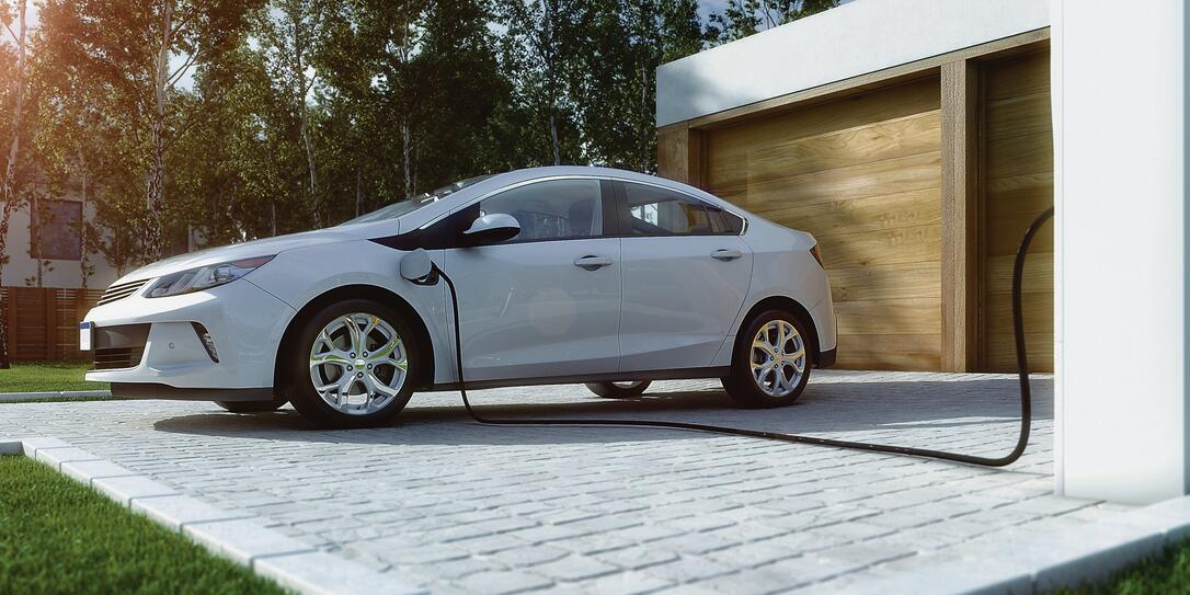 home electric car charging with solar power and wind power turbine in the background